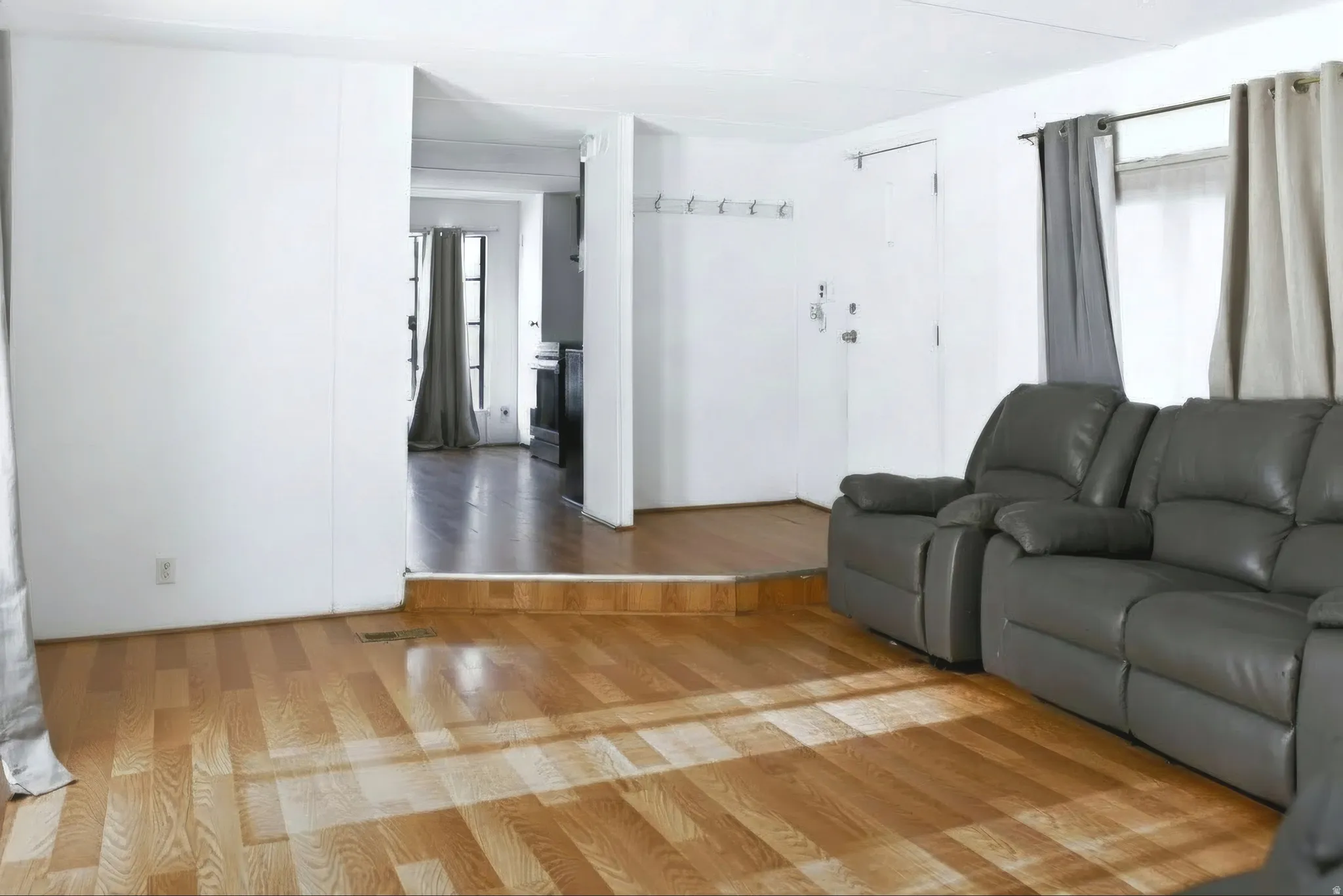 Spacious room featuring wood-finish flooring, white walls, and a recessed entryway