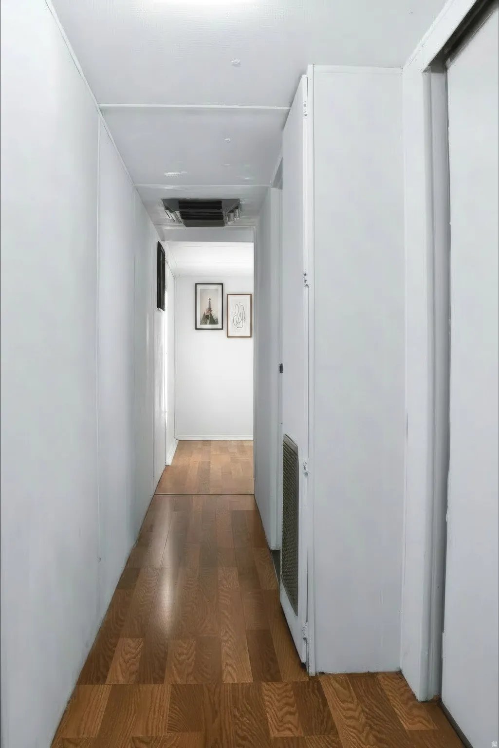 Hallway featuring wood-finish flooring, white walls, and a white ceiling with recessed lighting