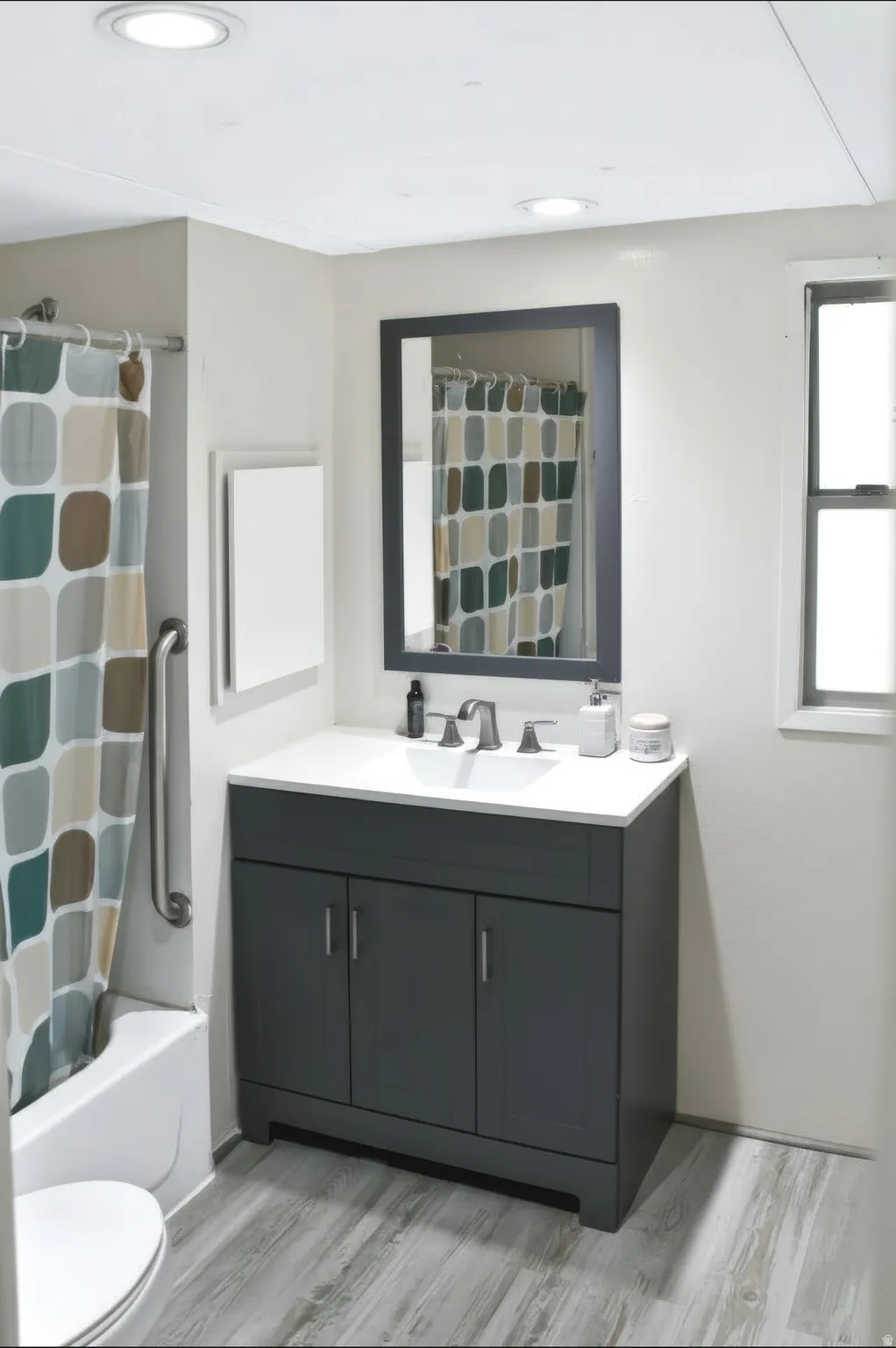 Bathroom featuring a dark gray vanity with chrome hardware, white countertop with integrated sink, rectangular framed mirror, and wood-finish flooring