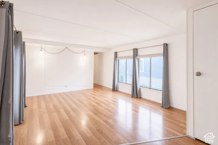Spacious interior featuring wood-finish flooring, multiple windows, and a built-in wall light fixture