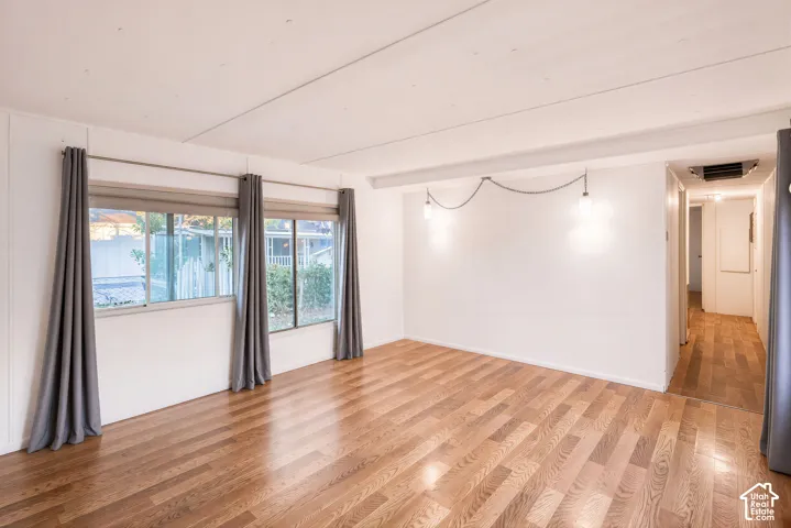 Wood-finish flooring throughout, multiple large windows, and suspended pendant lighting