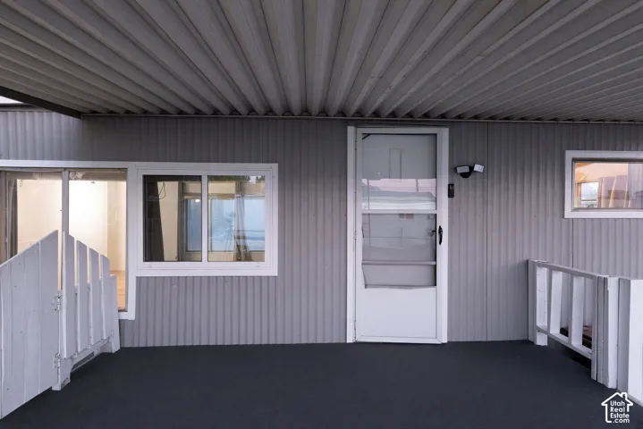 Covered outdoor porch with a solid entry door, white-framed windows, and white painted railings