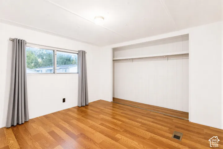 Hardwood-finish flooring, built-in closet storage, bright window, overhead lighting, and white wall finishes