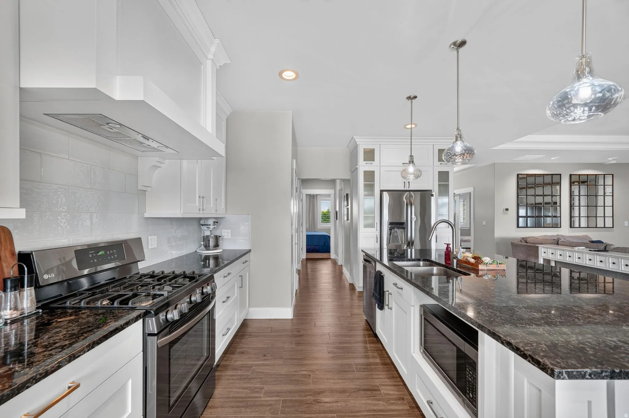 Modern kitchen featuring white cabinetry, dark granite countertops, stainless steel appliances, and a tiled backsplash