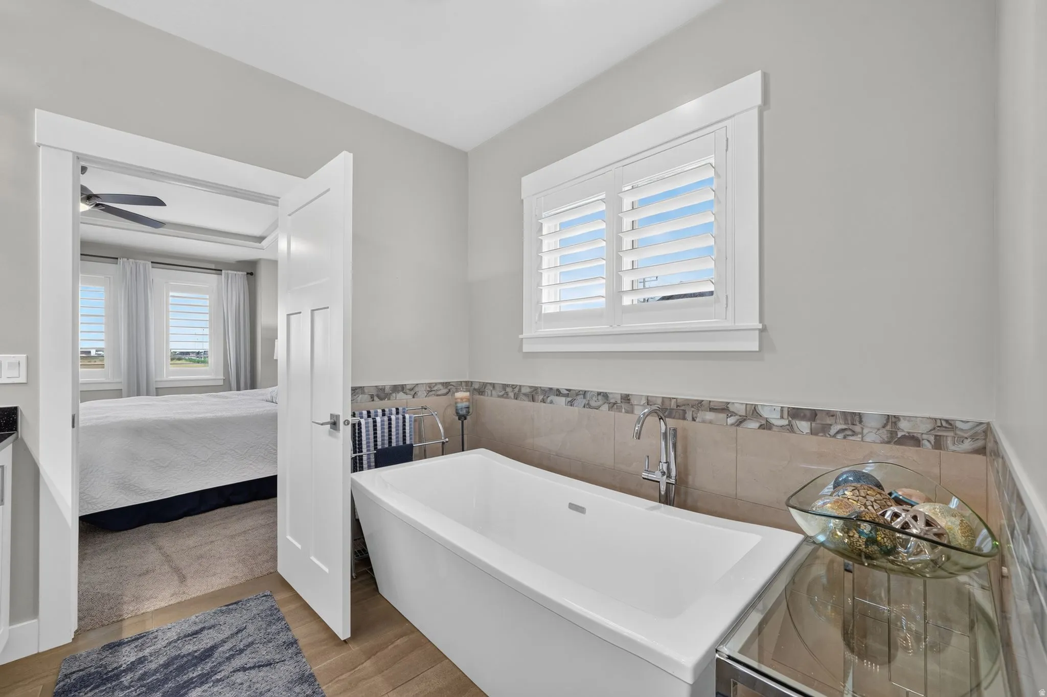 Freestanding soaking tub with a floor-mounted faucet, complemented by a tiled surround and an upper decorative tile band