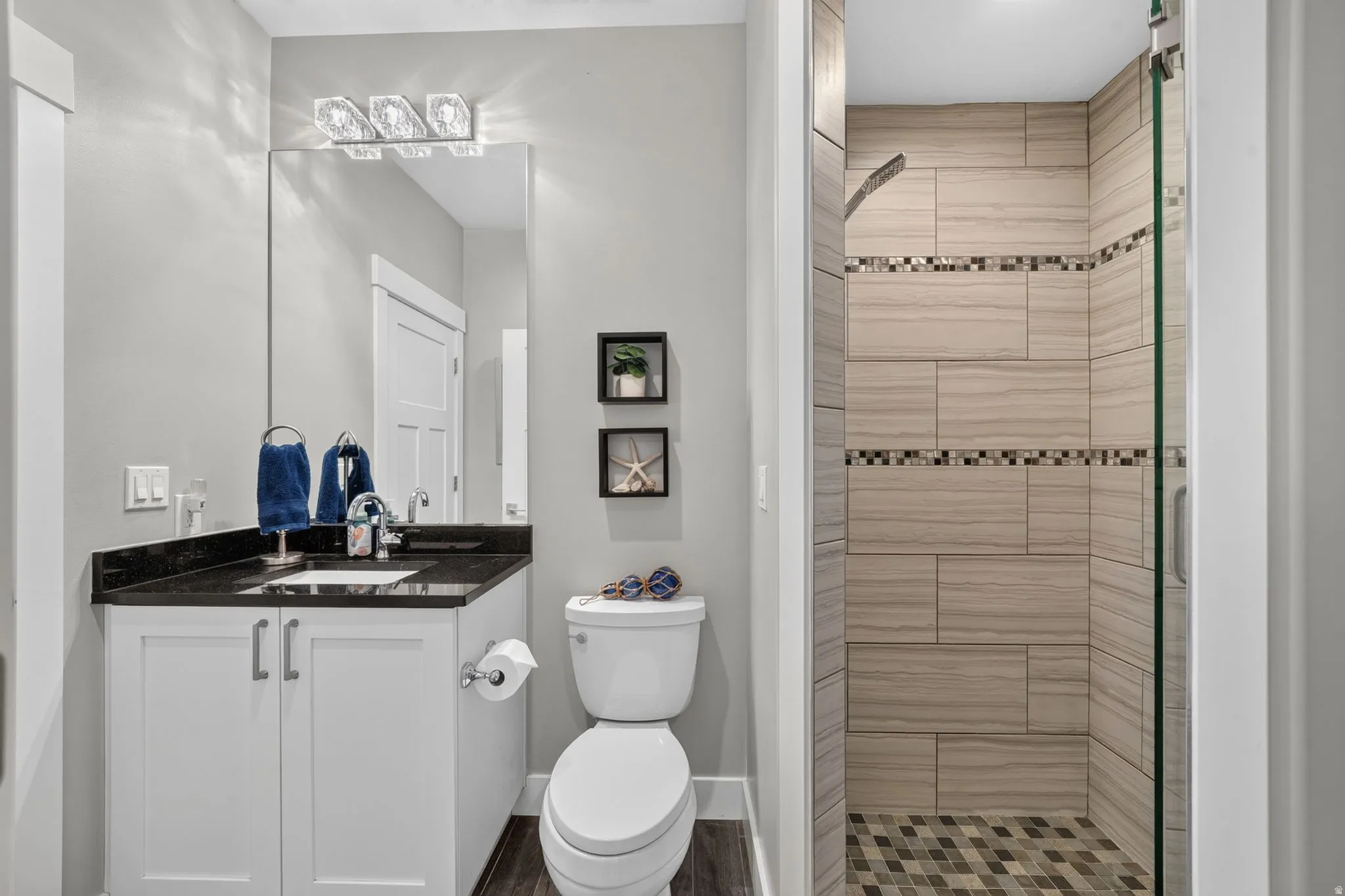 Full secondary bathroom featuring a walk-in shower with glass enclosure, tiled walls, and a mosaic floor