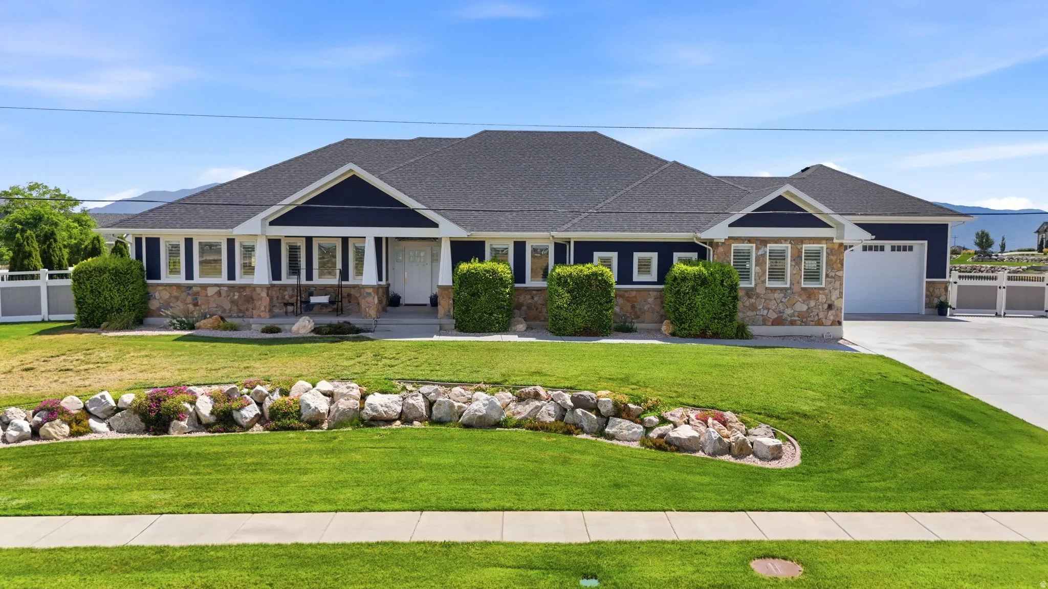 Ranch-style residence featuring a dark blue facade, stone accents, and a dark shingle roof