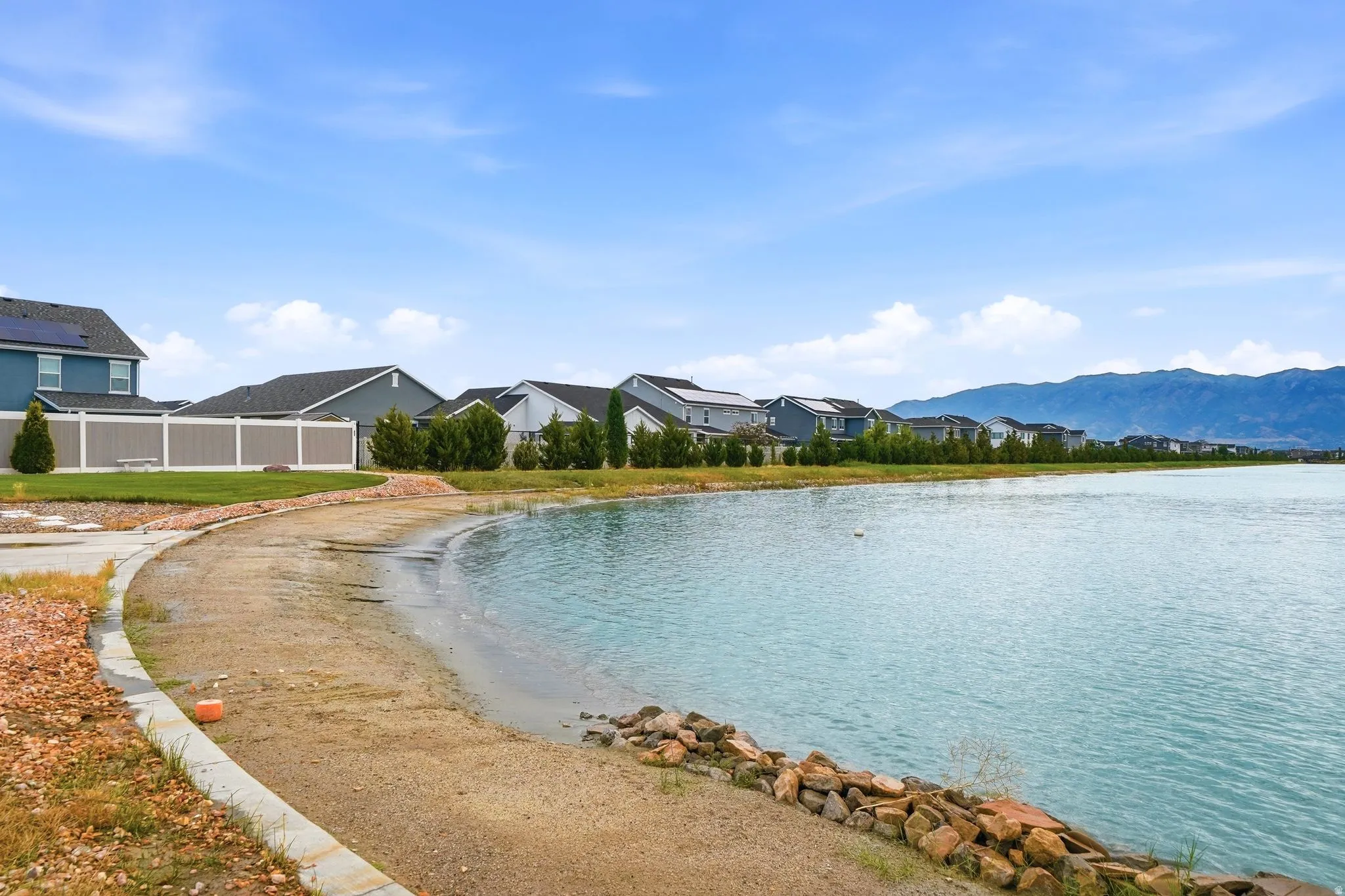 Private swimming cove with sandy beach, stone-lined shore and mountain backdrop