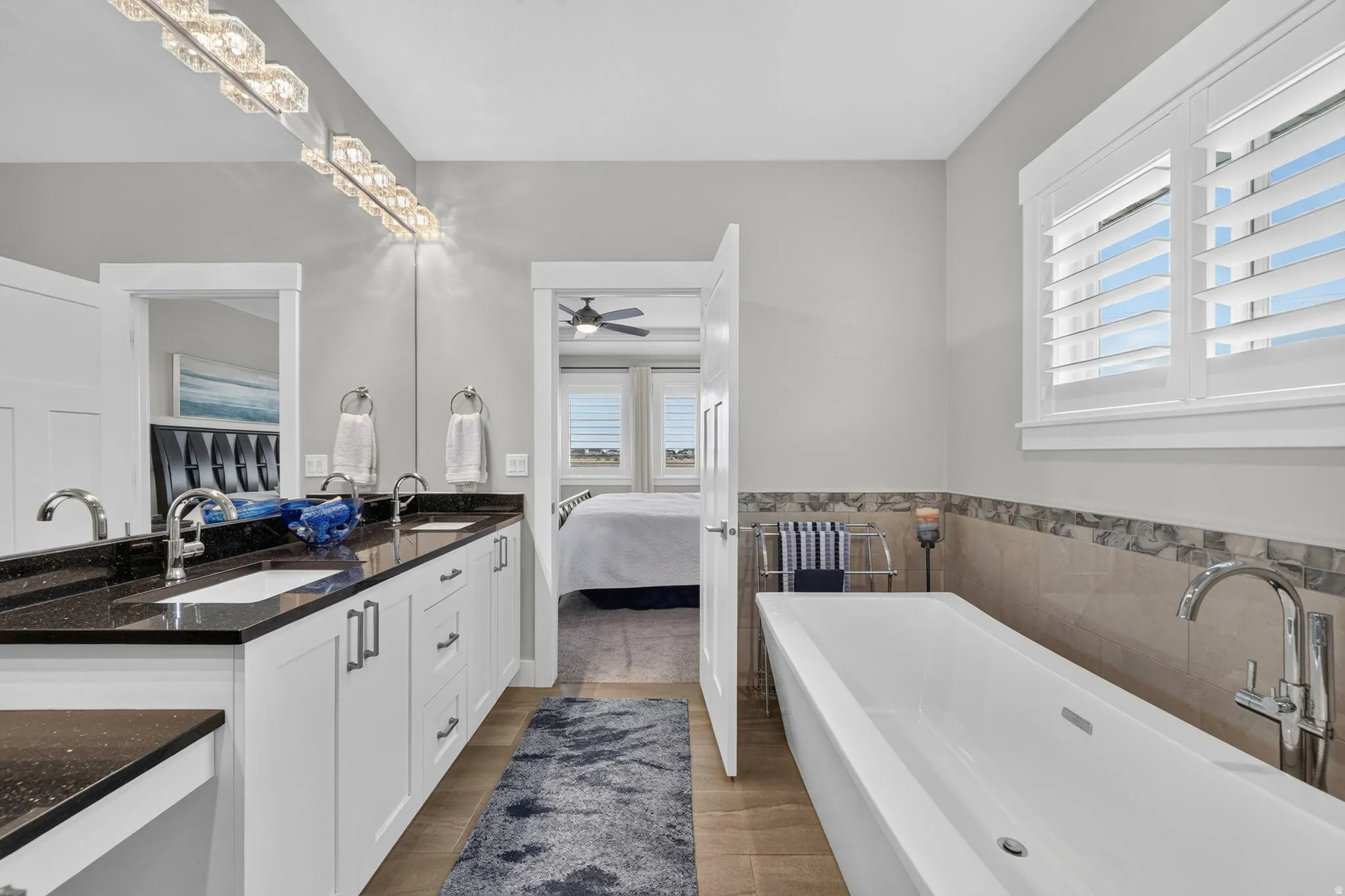 Modern bathroom featuring a freestanding tub, dual vanity with undermount sinks, and a large window with plantation shutters