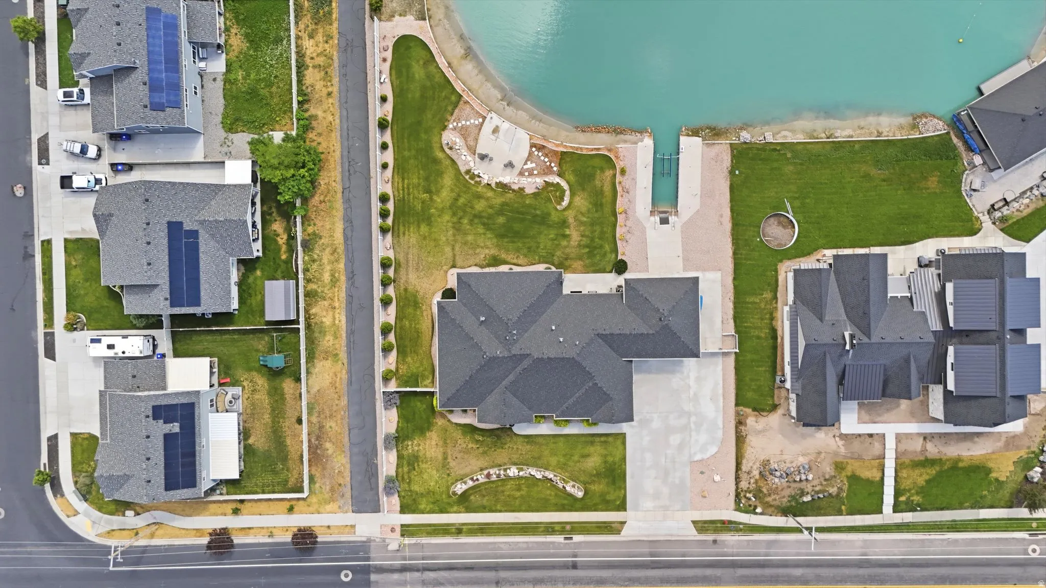 Waterfront property featuring a private boat ramp, direct lake access, expansive lawn, and a large paved driveway/ RV parking