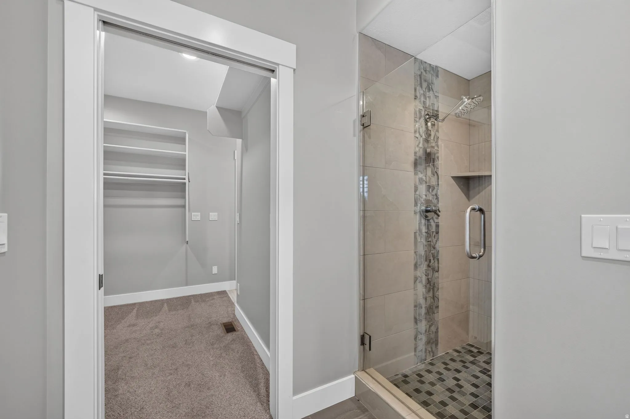 Huge walk-in shower featuring large format tile, a decorative vertical tile accent, and a mosaic tile shower pan