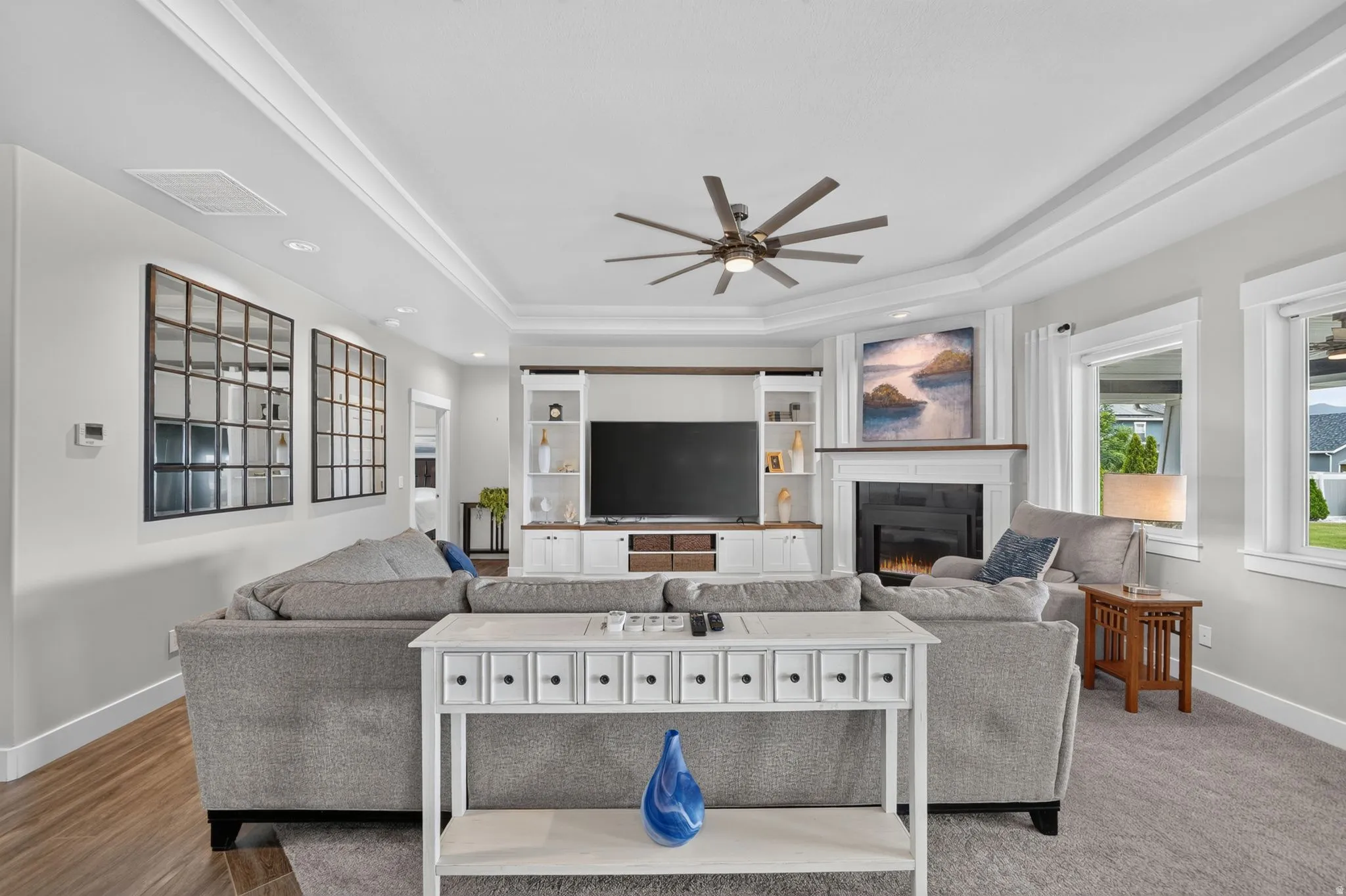 Spacious living area featuring a tray ceiling with crown molding, recessed lighting, and a contemporary ceiling fan