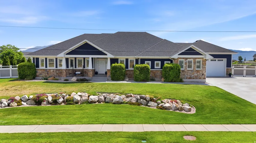 Ranch-style residence featuring a dark blue facade, stone accents, and a dark shingle roof