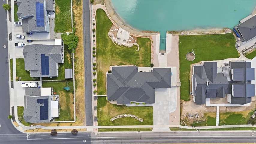Waterfront property featuring a private boat ramp, direct lake access, expansive lawn, and a large paved driveway/ RV parking