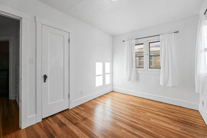 Interior room featuring wood-finish flooring, white painted walls, and white trim throughout
