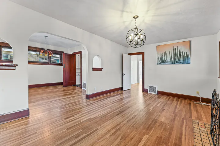 Spacious room featuring wood-finish flooring, white walls, and dark wood trim