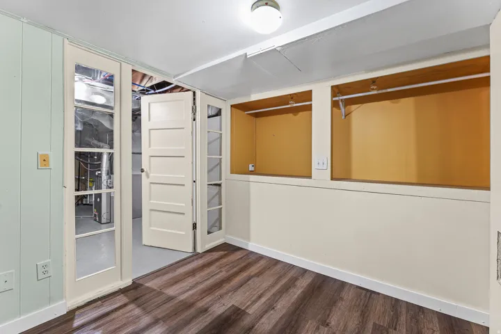 Finished interior space featuring wood-finish flooring, two built-in storage alcoves with hanging rods, a ceiling-mounted light fixture, and a paneled door with glass inserts