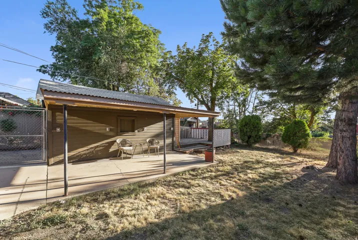 Detached outbuilding with a corrugated metal roof, wood siding, and an attached covered patio