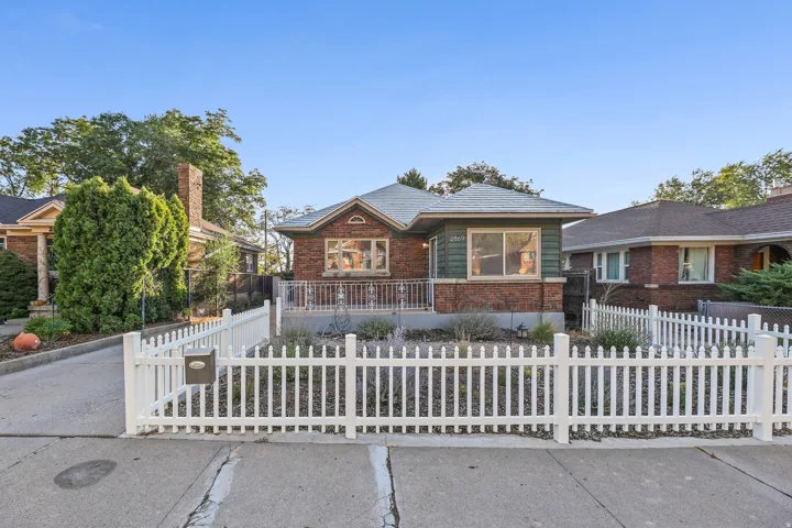 Brick exterior with a peaked roofline, front porch, and white picket fence