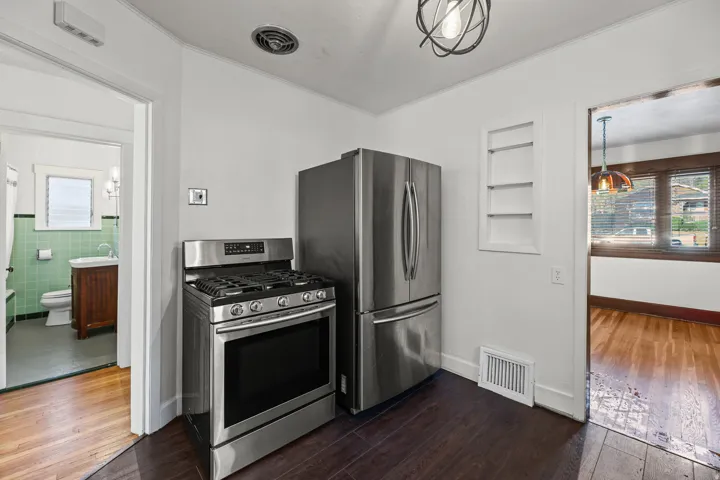 Stainless steel gas range and refrigerator feature prominently in this kitchen area