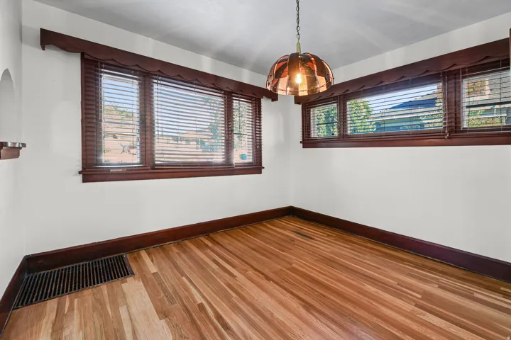 Spacious room featuring light wood-finish flooring, white walls, and dark wood trim