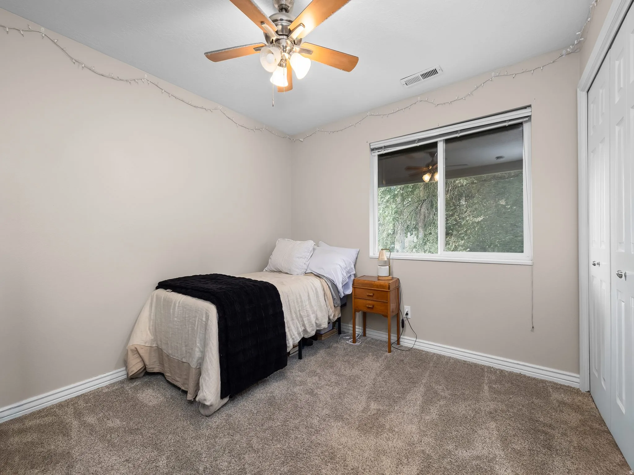 Carpeted room featuring a ceiling fan with integrated lighting, a dual-pane window, and white baseboards