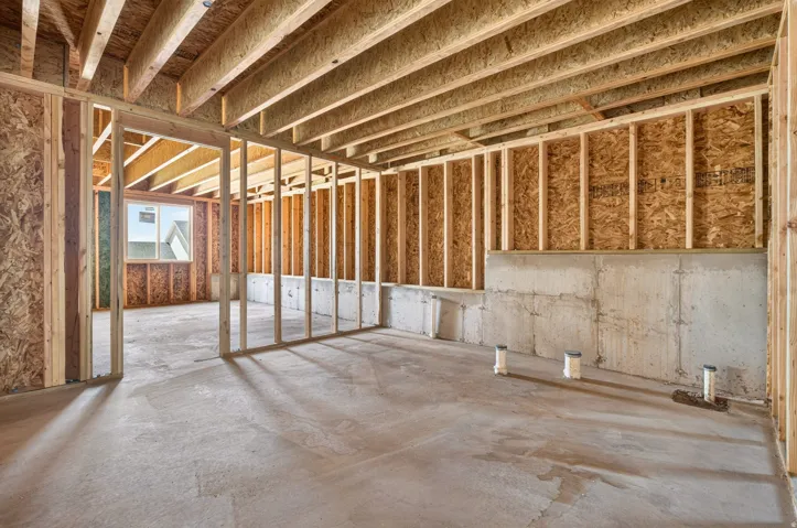 Unfinished basement featuring wood framing, exposed ceiling joists, concrete flooring, and a visible window
