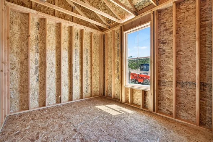 Framed interior space featuring exposed wood studs and oriented strand board (OSB) sheathing