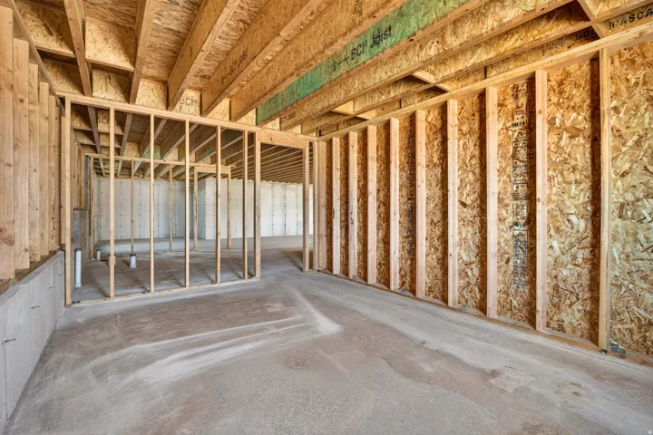 Unfinished basement featuring exposed wood framing, concrete flooring, and visible joists