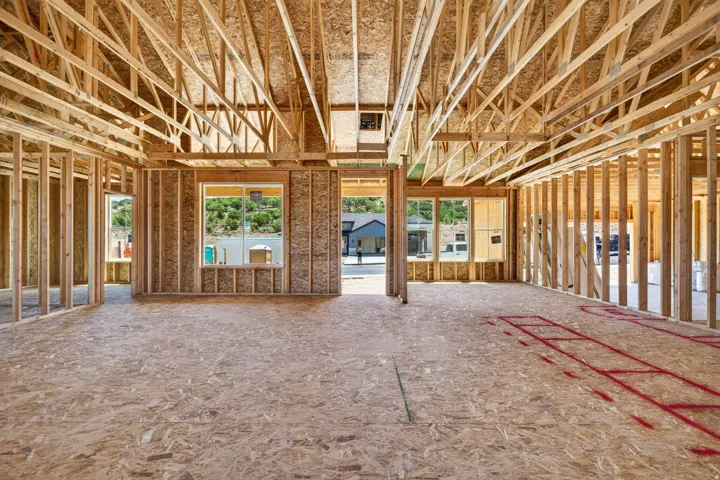 Open concept residential framing featuring engineered wood flooring and exposed ceiling trusses
