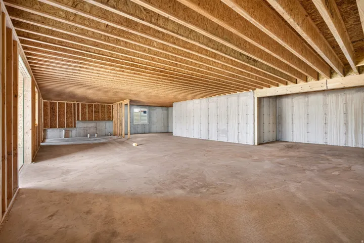 Unfinished lower level featuring exposed wood joists, concrete flooring, concrete foundation walls, and framed interior walls
