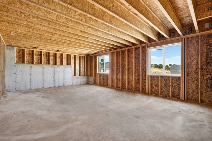 Unfinished basement with concrete flooring and exposed wood framing