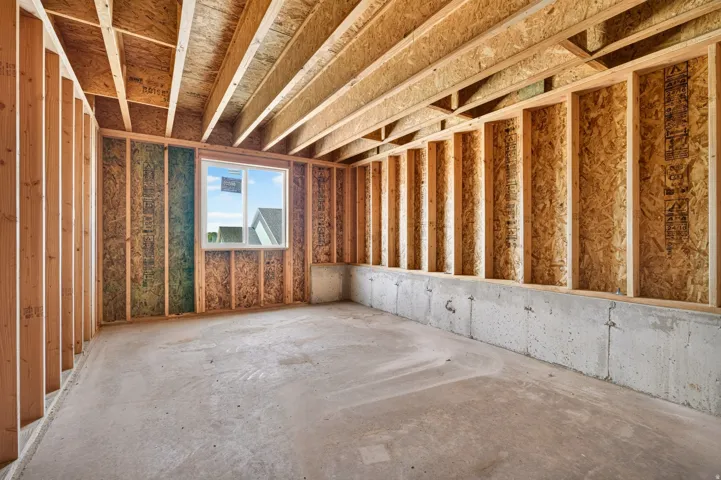 Unfinished basement featuring exposed wood framing and concrete walls