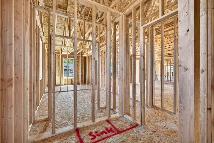Interior framing showcasing structural wood beams, plywood subflooring, and multiple window openings