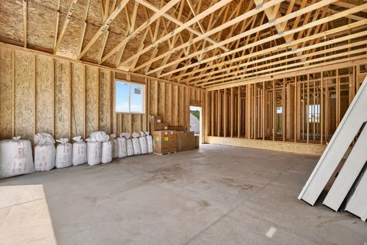 New construction framing showcasing open trusses, wood stud walls, and a concrete slab floor
