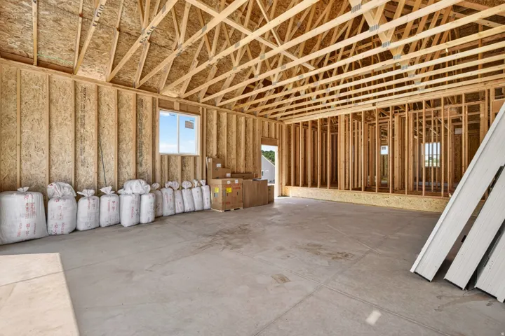 Unfinished interior space featuring exposed wood framing, oriented strand board walls, and a concrete floor