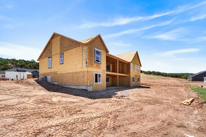 Two-story property under construction featuring a framed structure, plywood sheathing, and a multi-level deck
