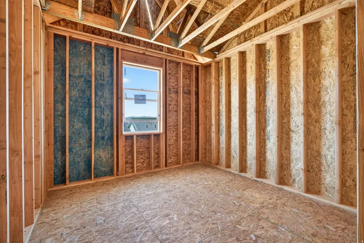 Unfinished interior room featuring exposed wood framing, oriented strand board subflooring, and a double-hung window