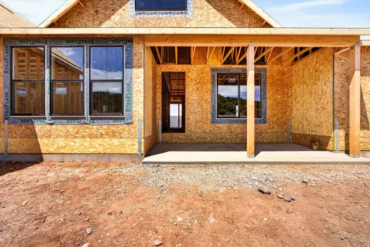 New construction exterior featuring a covered entry, exposed wood framing, and multiple window openings