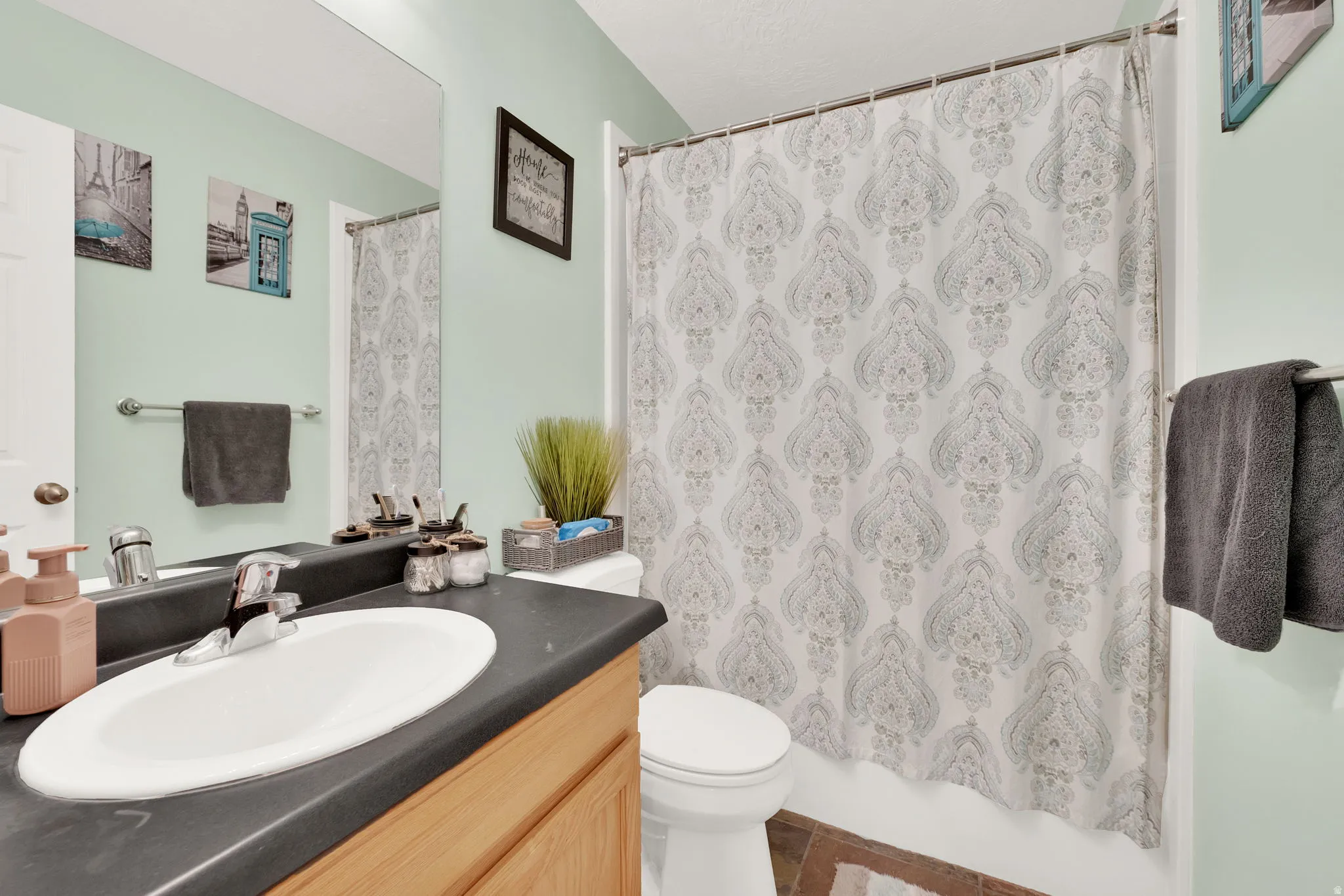 Bathroom featuring a single vanity with a dark countertop, an integrated oval sink, and wood-finish cabinetry