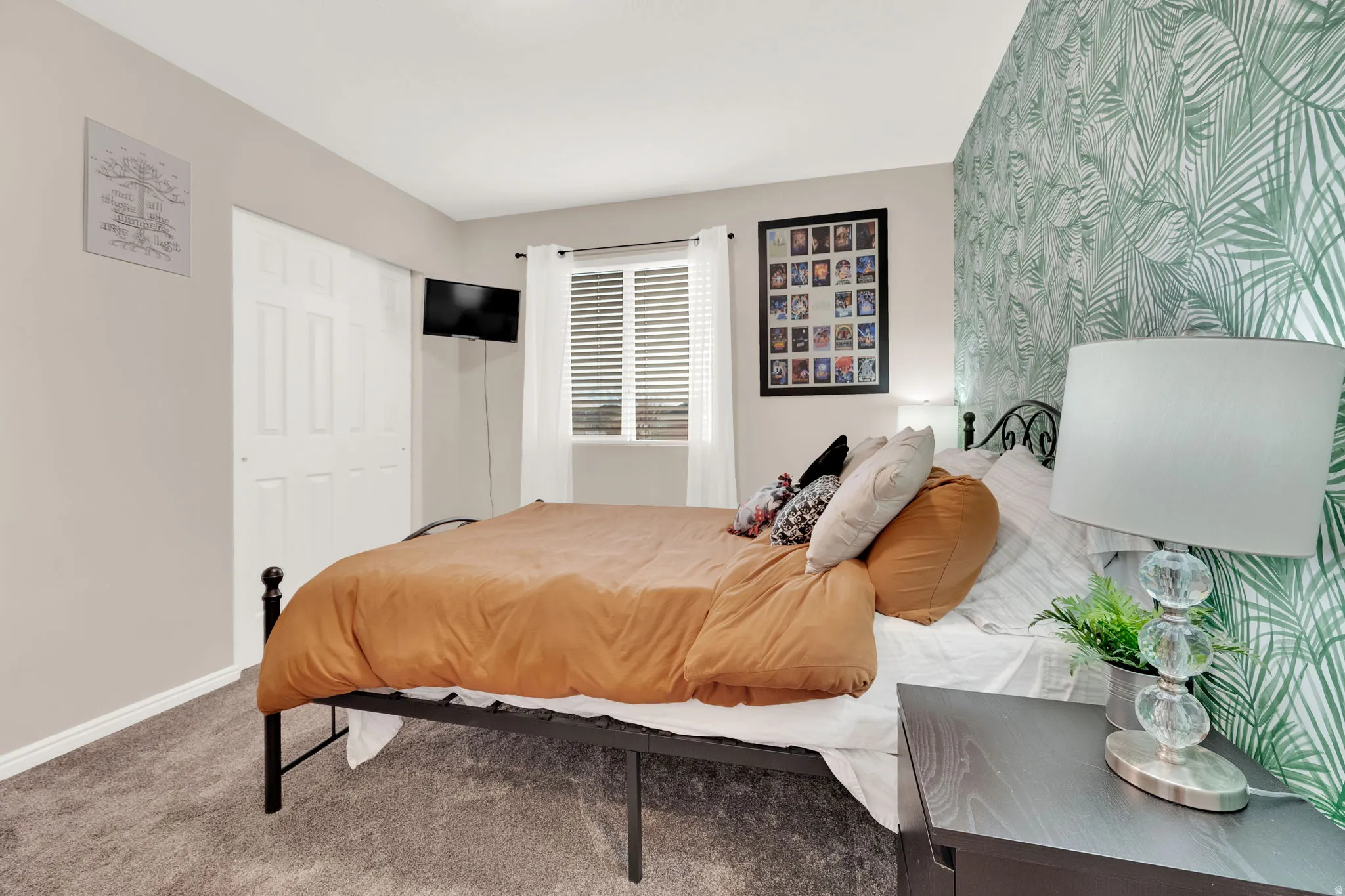 Bedroom featuring a patterned accent wall, neutral carpeting, and white baseboards