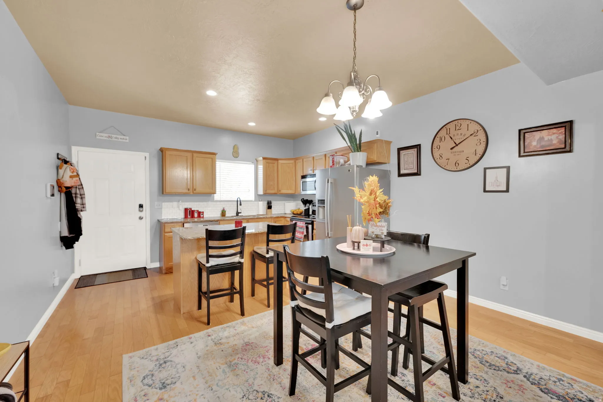 Open-concept kitchen and dining area featuring wood-finish flooring, light wood cabinetry, and a kitchen island with seating