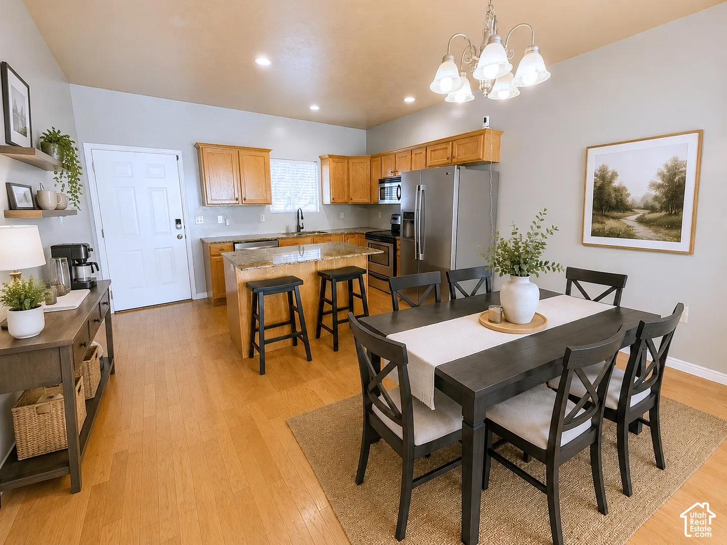 Open-concept kitchen and dining area featuring warm wood cabinetry, stone countertops, wood-finish flooring, and recessed lighting