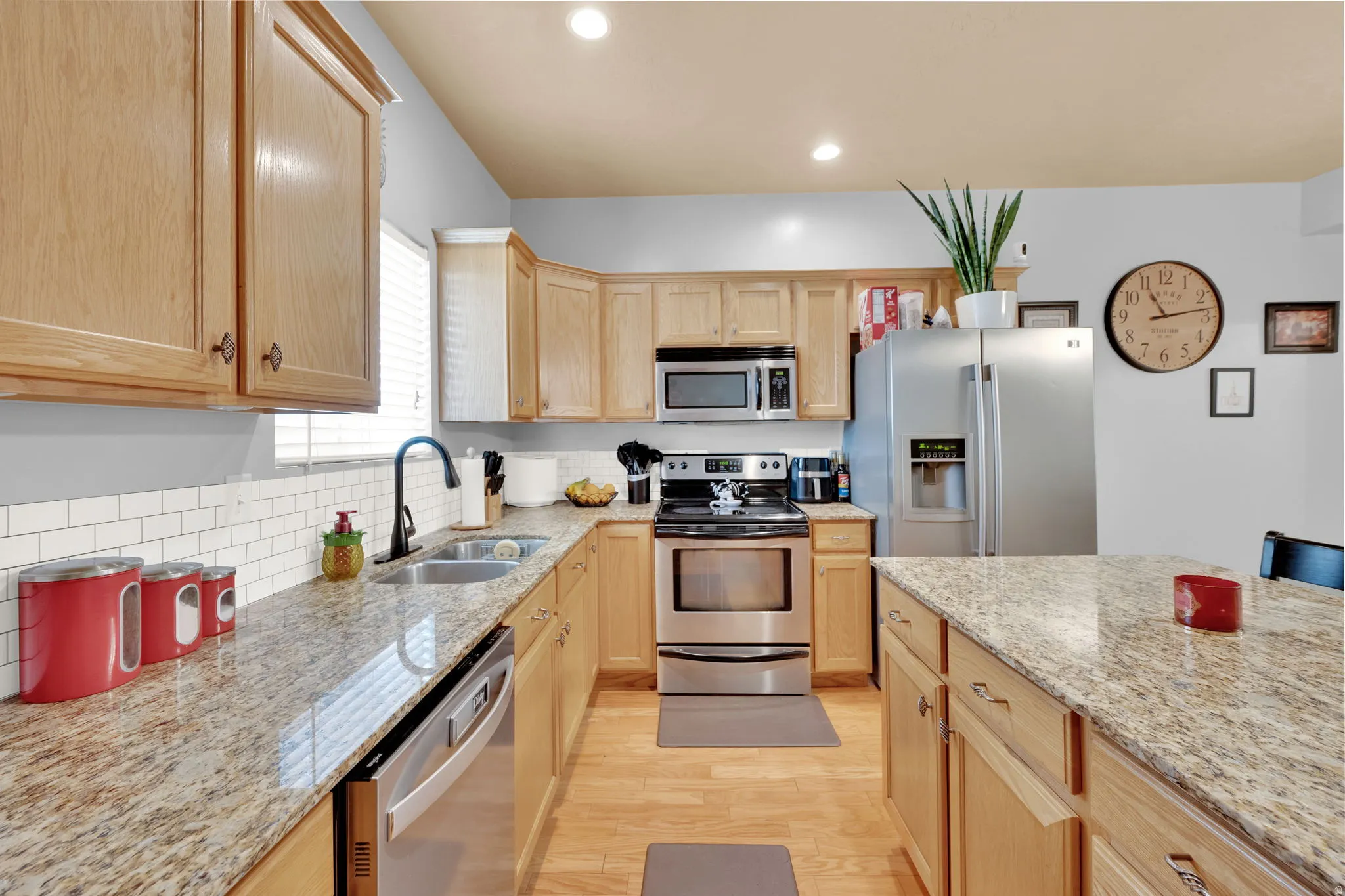 Kitchen featuring granite countertops, wood-finish cabinetry, stainless steel appliances, a subway tile backsplash, and recessed lighting