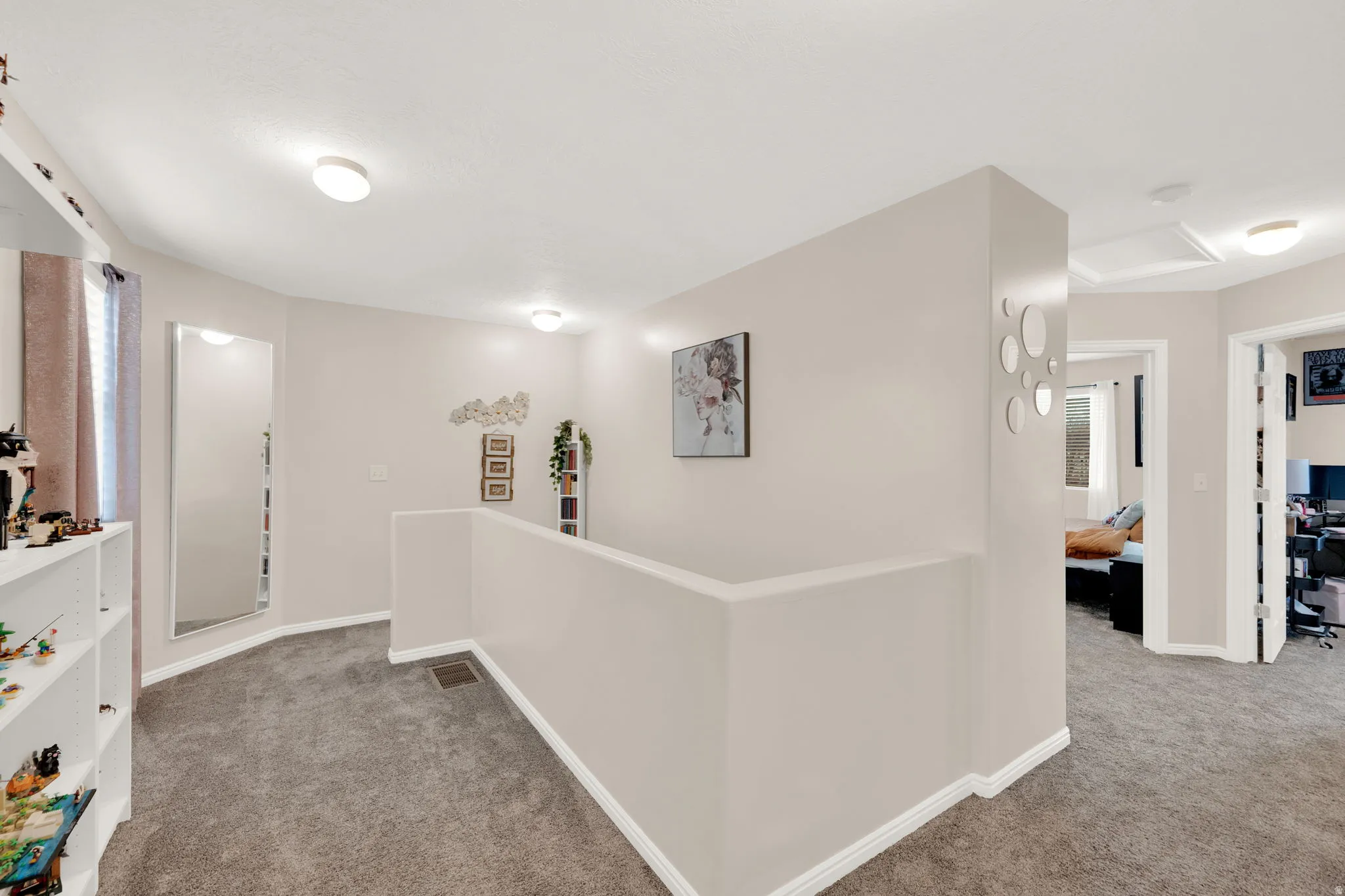 Carpeted hallway featuring a neutral color palette, recessed lighting, white baseboards, and multiple doorways leading to additional rooms