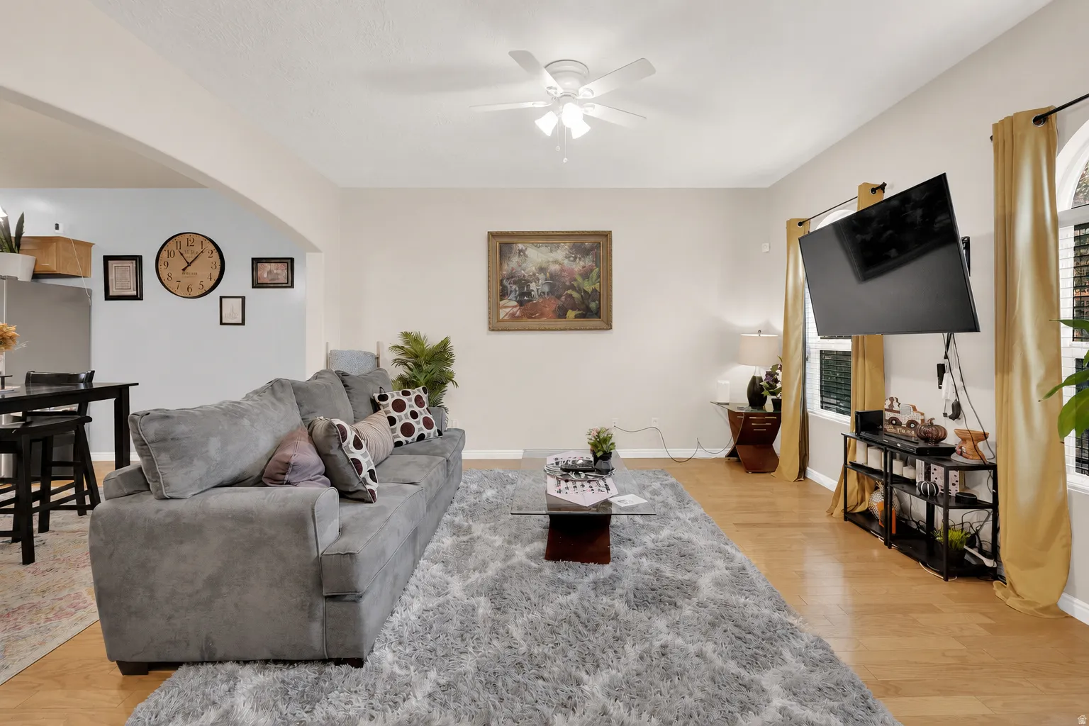 Spacious living area featuring wood-finish flooring, light neutral wall tones, and arched windows