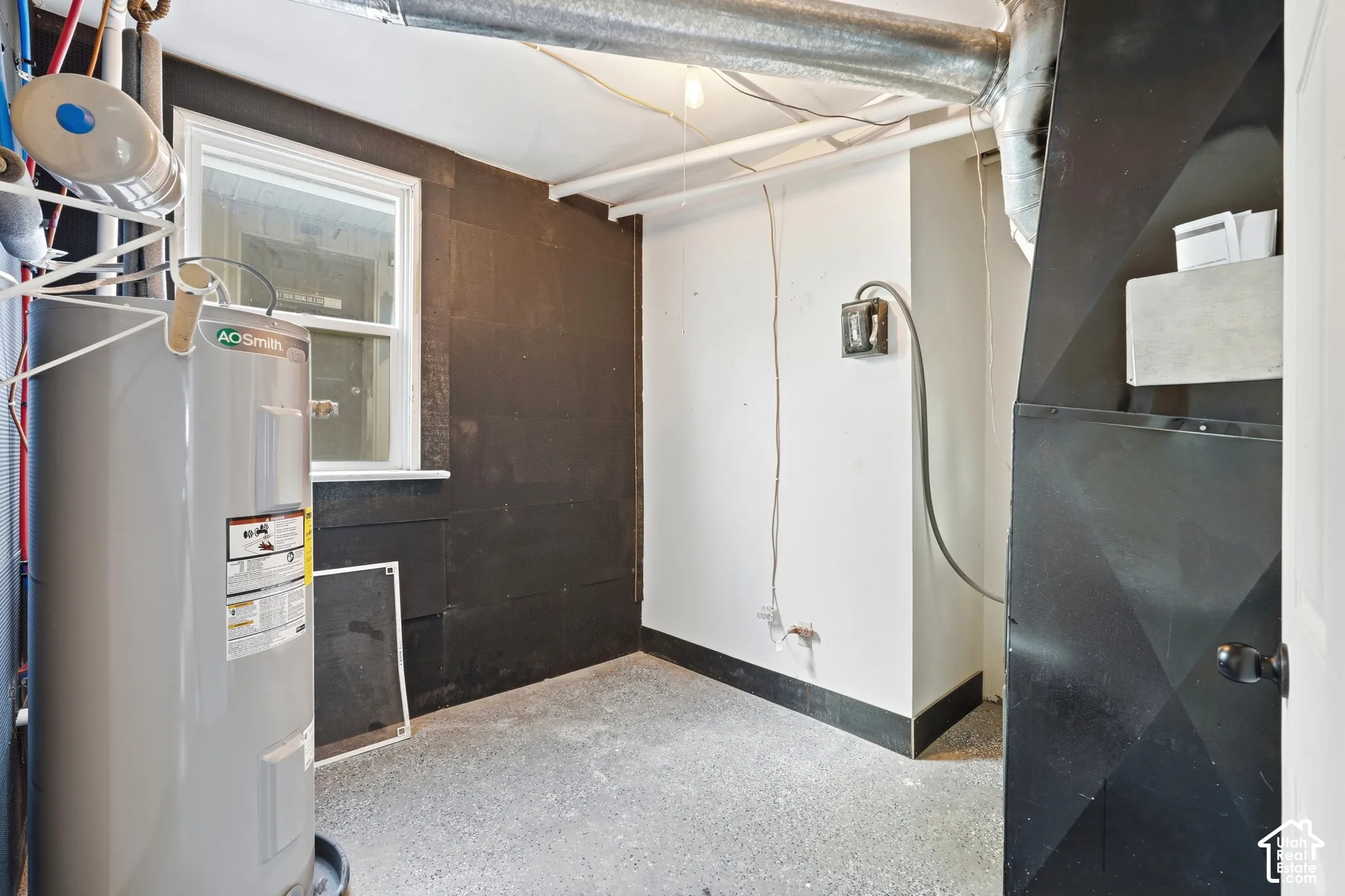 Utility area featuring a water heater, white-framed window, and exposed ductwork