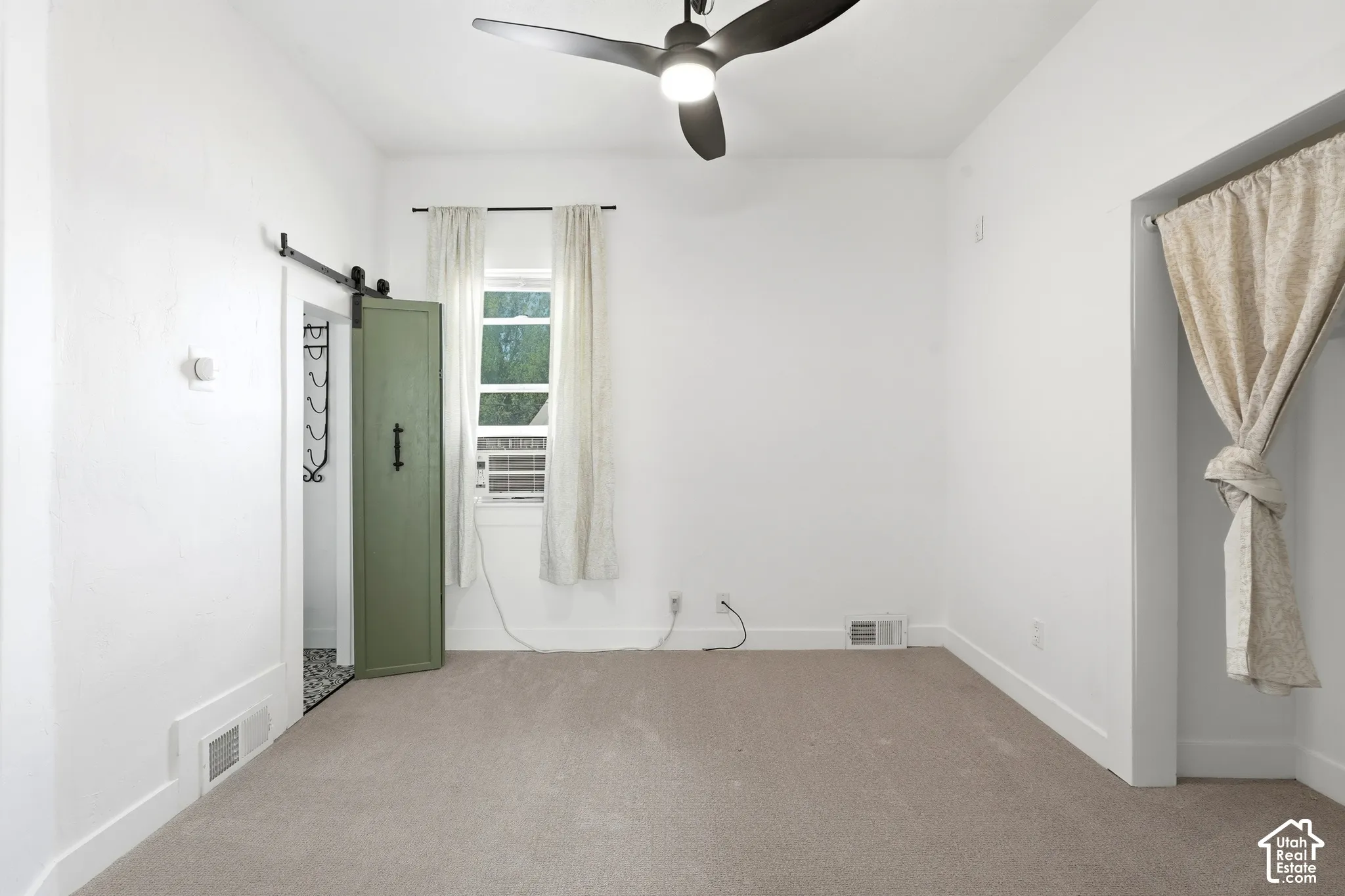 Bright room featuring neutral wall paint, light-toned carpeting, a contemporary ceiling fan, and a window with natural light