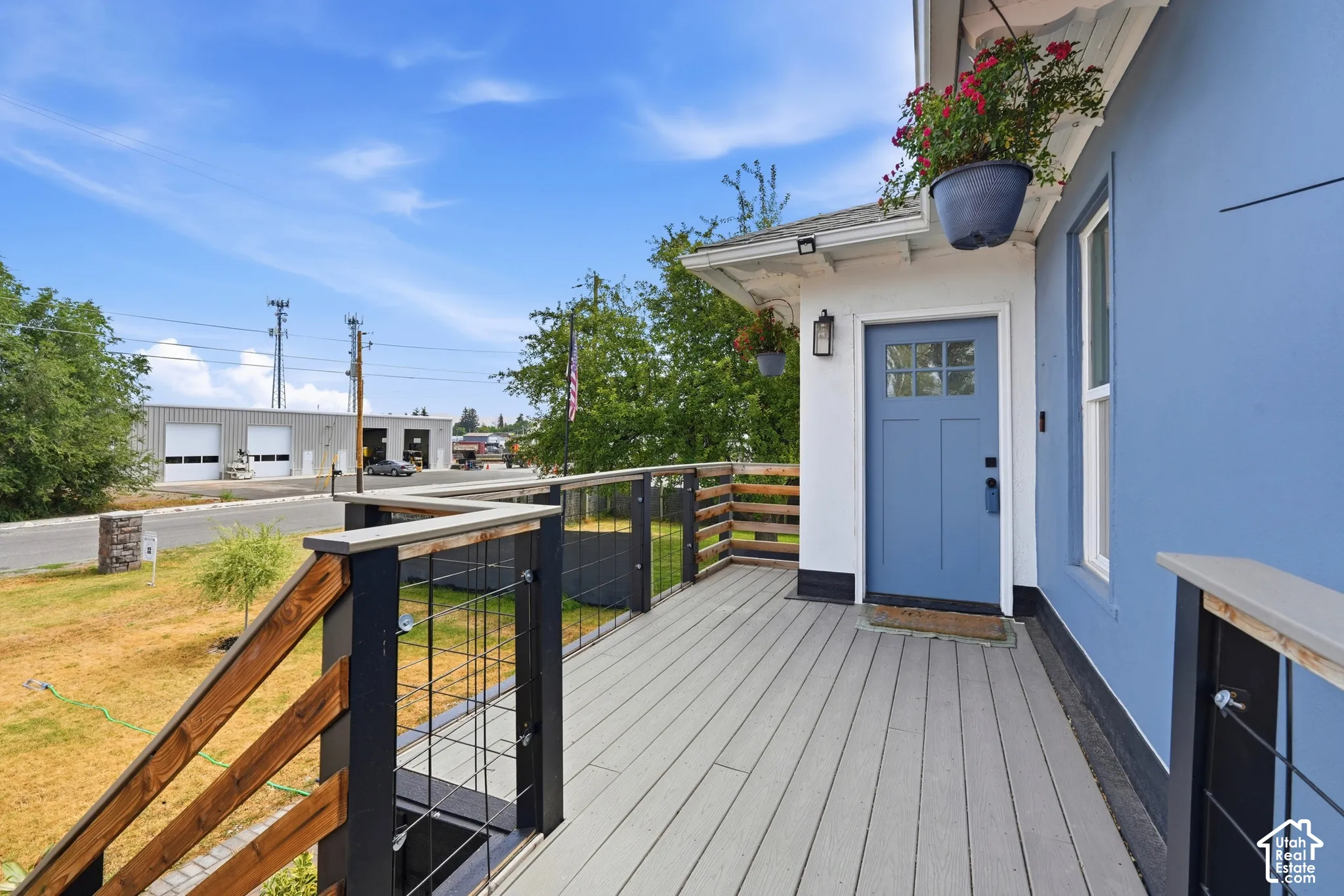 Spacious outdoor deck featuring composite decking, wood and metal railings, and a blue entry door with clear glass lites