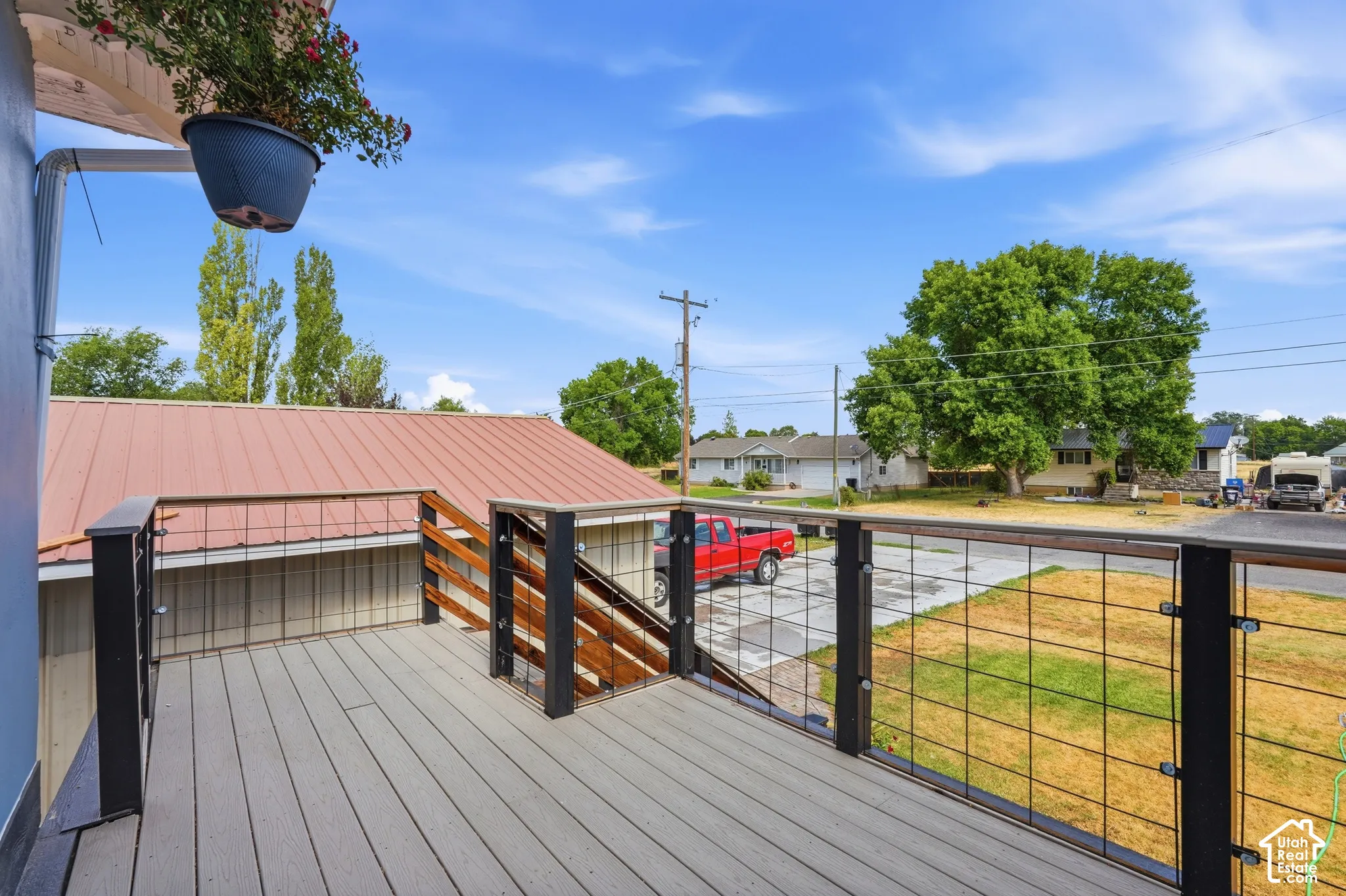 Spacious deck featuring composite decking, black metal wire railings, and wooden stair railings